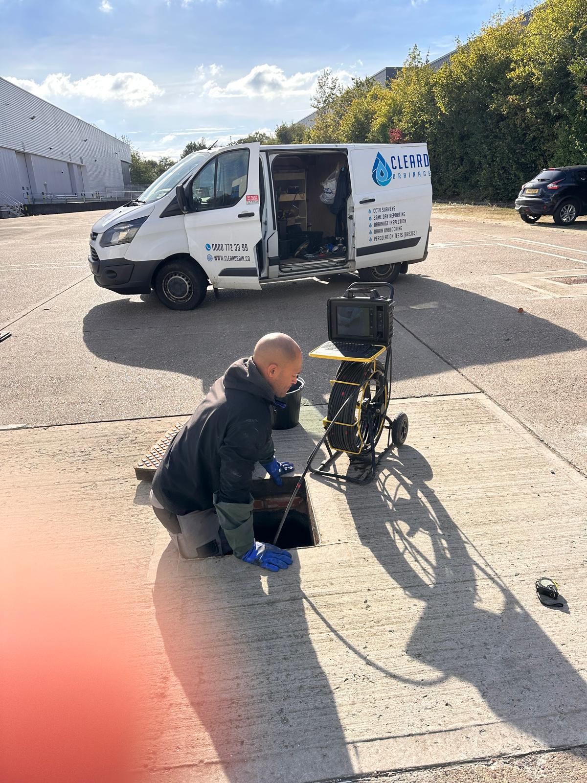 An open manhole with survey equipment set up alongside it