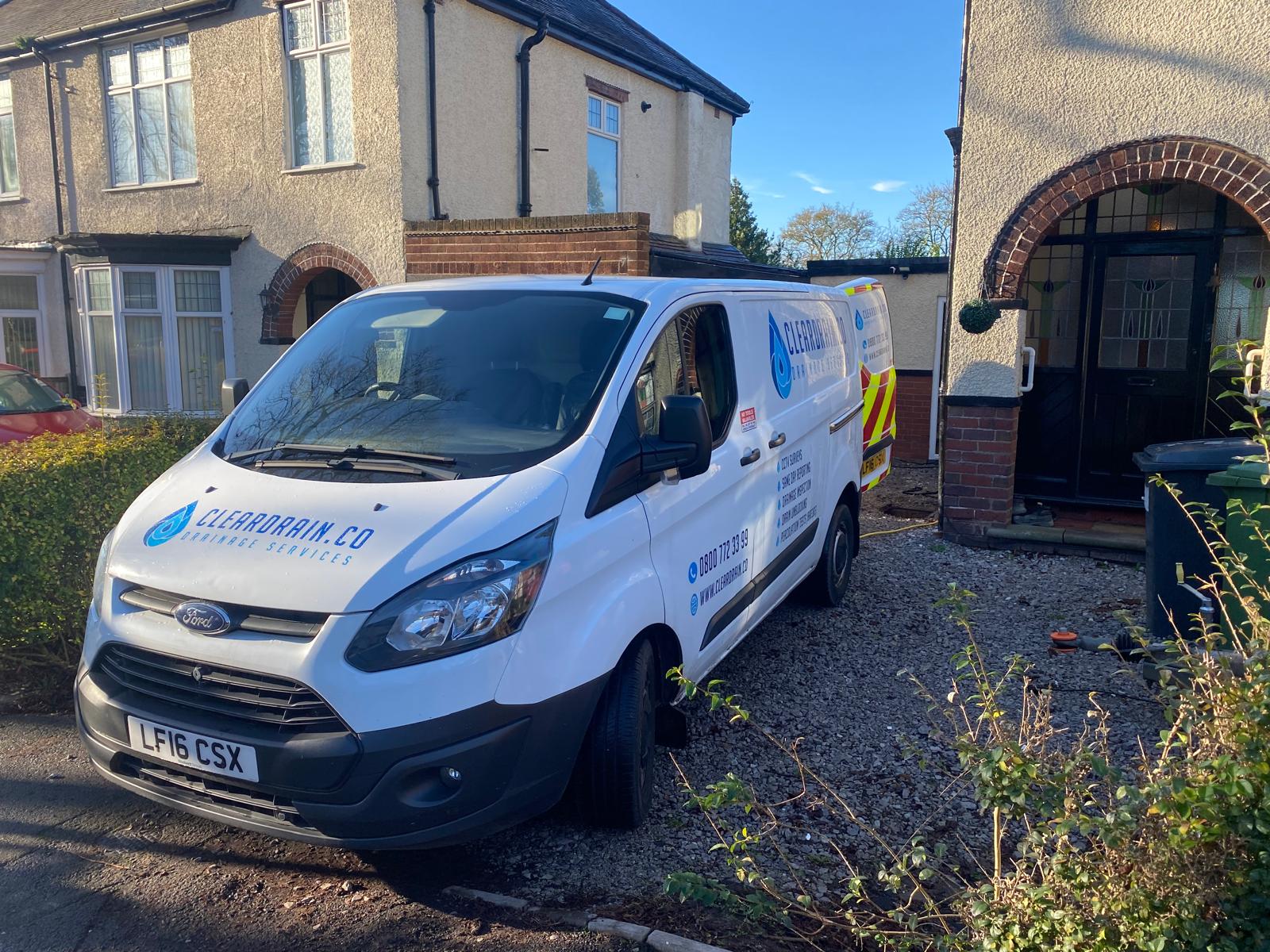 A Clear Drain van outside a house on a quiet residential road
