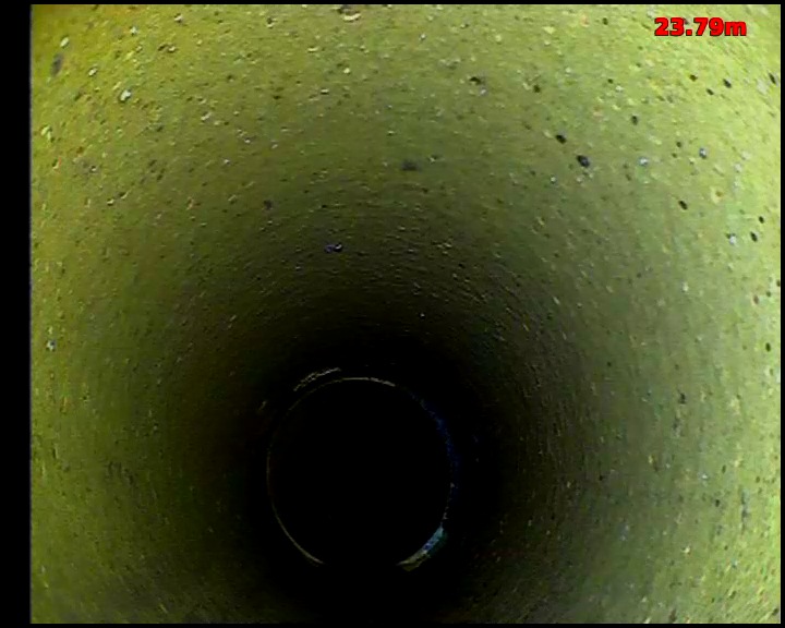 CCTV view along a drain with green staining across the pipe wall