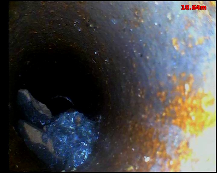 CCTV view inside a drain showing debris resting in the bottom of the pipe, partly obstructing the bore
