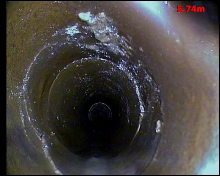 CCTV view inside a drain showing hard deposits built up on the pipe wall around a joint