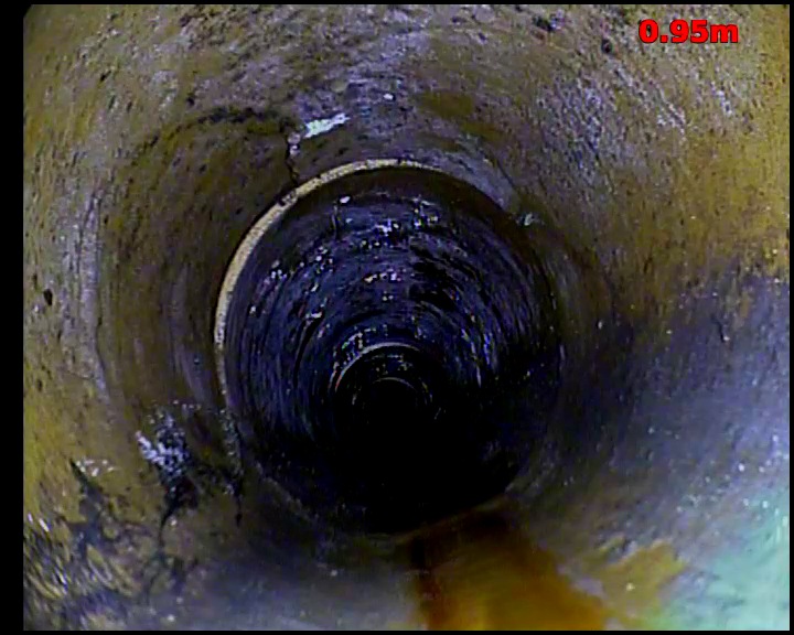 CCTV view looking along a drain through a series of pipe joints receding into the distance