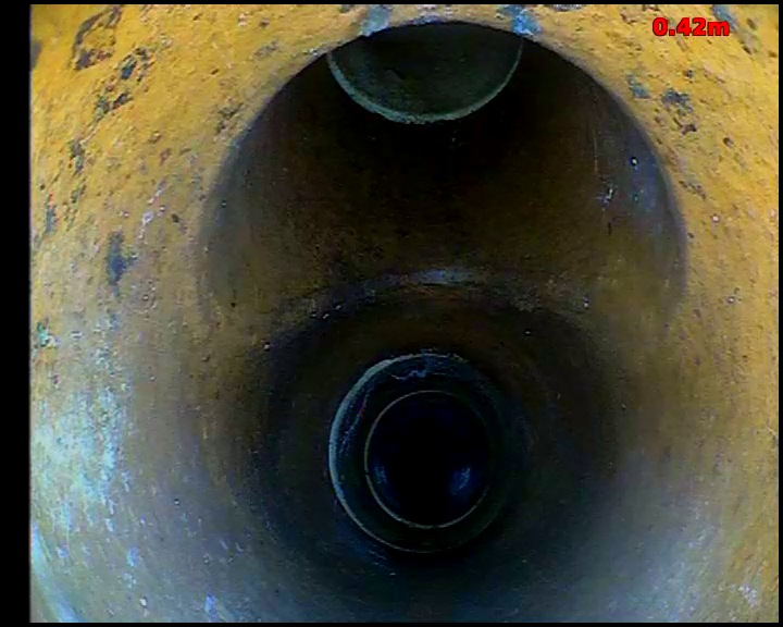 CCTV view looking along a drain through several pipe joints receding into the distance